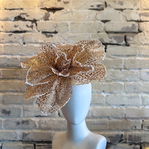May include: A gold and white flower-shaped hat with a textured surface.