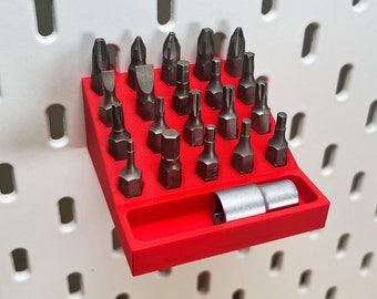 May include: A red plastic organizer with a variety of screwdriver bits and a socket. The organizer is mounted on a pegboard wall.