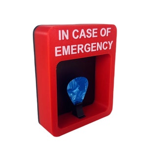 May include: Red plastic box with the text "IN CASE OF EMERGENCY" in white letters. The box has a slot for a guitar pick, and a blue guitar pick is inside the slot.
