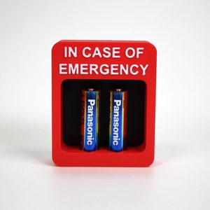 Può includere: Scatola rossa con il testo "IN CASE OF EMERGENCY" e due batterie Panasonic all'interno.