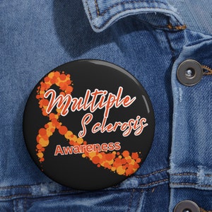 May include: A black button with an orange and yellow ribbon design. The text "Multiple Sclerosis Awareness" is written on the button.
