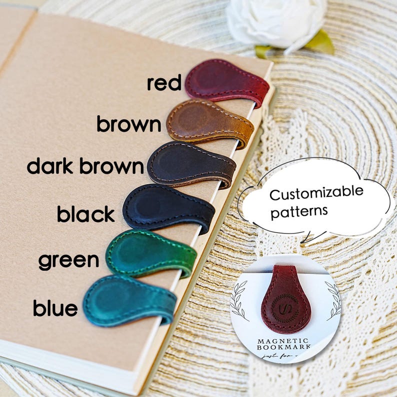 Pu&ograve; includere: Segnalibri magnetici in pelle rossa, marrone, marrone scuro, neri, verdi e blu. Ogni segnalibro &egrave; attaccato al bordo di un taccuino. L'immagine mostra anche un segnalibro rosso con il testo "Magnetic Bookmark" e "Customizable patterns".