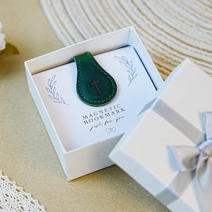 Pu&ograve; includere: Un segnalibro magnetico in pelle verde con un design a croce, presentato in una confezione regalo bianca. La scatola contiene una carta con le parole "MAGNETIC BOOKMARK" e "just for you."