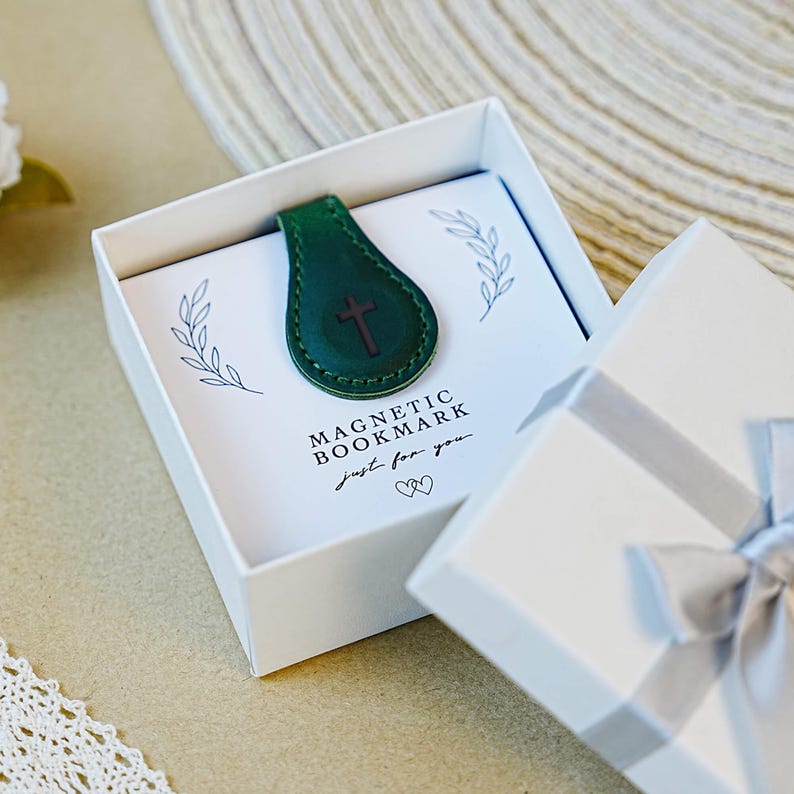 Pu&ograve; includere: Un segnalibro magnetico in pelle verde con un design a croce, presentato in una confezione regalo bianca. La scatola contiene una carta con le parole "MAGNETIC BOOKMARK" e "just for you."