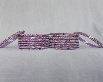 May include: A set of purple bangles with iridescent rhinestones. The bangles are stacked on top of each other and are arranged in a semi-circle.