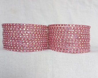May include: A set of pink glass bangles with iridescent glitter. The bangles are stacked in two rows.