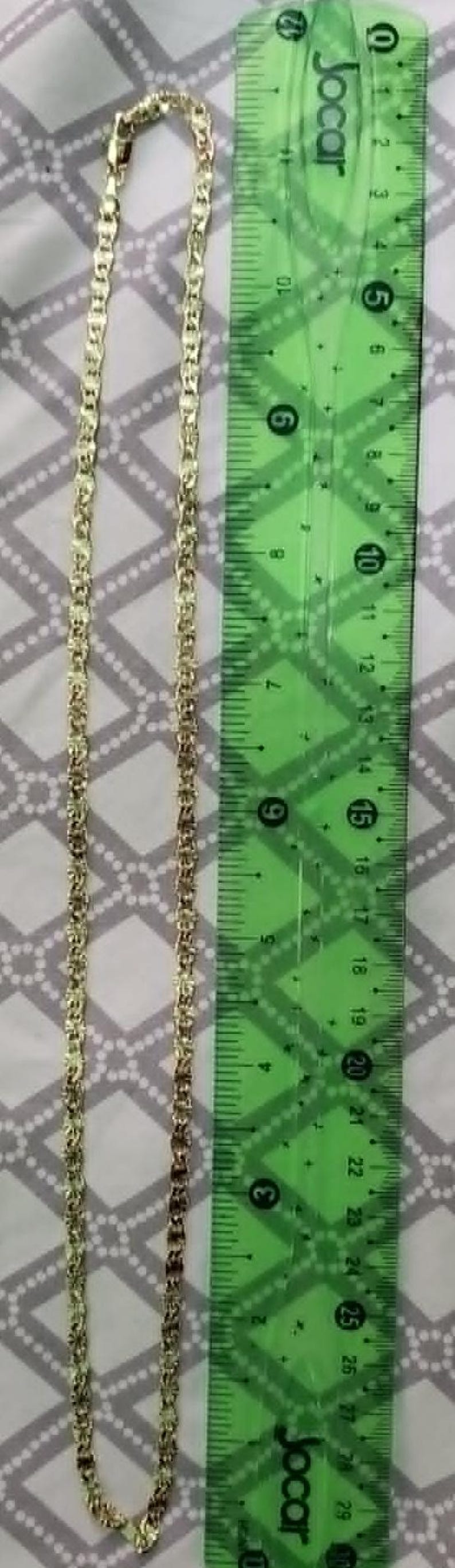 May include: A gold-colored chain necklace with a repeating pattern of rectangular links. The necklace is approximately 29 cm long, as measured by a green ruler with the brand name "Jocar".
