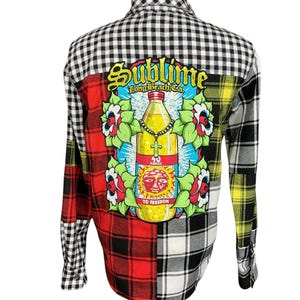 May include: A long-sleeved flannel shirt with a patchwork design in red, black, white, and yellow. The back features a graphic of a bottle with the text "Sublime Long Beach, CA" and "To Freedom."