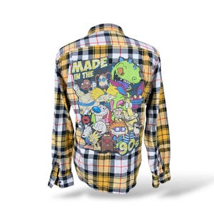 May include: A long-sleeved flannel shirt with a yellow, black, and white plaid pattern. The back features a colorful graphic of cartoon characters and the text "MADE IN THE 90s".