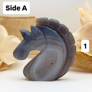 May include: A carved stone sculpture of a horse's head. The sculpture is primarily gray and white with a polished finish. The text "Side A" is in the upper left corner, and the number "1" is in the upper right corner.