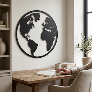 May include: A circular black metal wall art piece featuring a detailed silhouette of the world map. The continents are connected to a thin outer circular frame, creating a cutout design that displays the wall color through the landmasses.