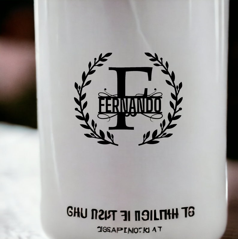 K&ouml;nnte beinhalten: Wei&szlig;e Flasche mit einem schwarzen Kranzdesign und dem Buchstaben F in der Mitte. Der Text "Fernando" befindet sich innerhalb des Kranzes. Der Text "GHU 1217 EI PEILTMH T6" befindet sich am Boden der Flasche.