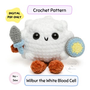 May include: A white crocheted plush toy of a white blood cell named Wilbur, holding a sword and shield. The toy has black eyes and orange feet. Text on the image reads "Crochet Pattern", "Digital PDF Only", "No-Sew", and "Wilbur the White Blood Cell".
