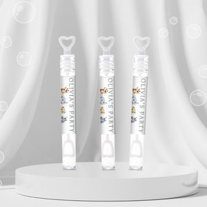 Puede incluir: Tres varitas de burbujas de plástico transparente con mangos en forma de corazón. Cada varita tiene una etiqueta blanca con el texto "Olivia's Party" y un diseño de animales de dibujos animados.