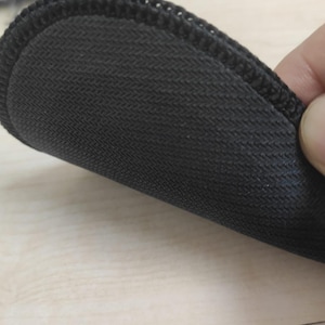 May include: A circular black coaster featuring a textured, non-slip rubber base with a distinct herringbone pattern. The edge of the coaster is finished with a durable, tightly stitched black fabric border that provides a clean, uniform appearance.