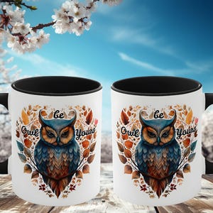 May include: Two black and white coffee mugs with a black handle. The mugs have a white background with a colorful owl illustration and the text "Be Owl Yourselves".