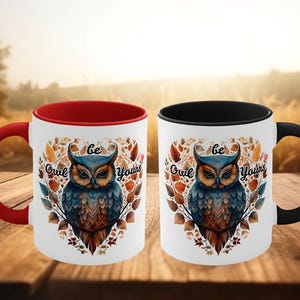 May include: Two white ceramic mugs with red and black rims. Both mugs feature a colorful owl illustration with the text "Be Owl Yours".