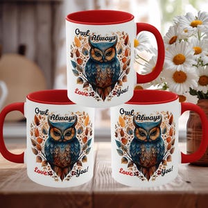 May include: Three white ceramic mugs with red handles and interiors. Each mug features a watercolor owl design with the text "Owl Always Love You!". The mugs are on a wooden surface, with a vase of flowers in the background.