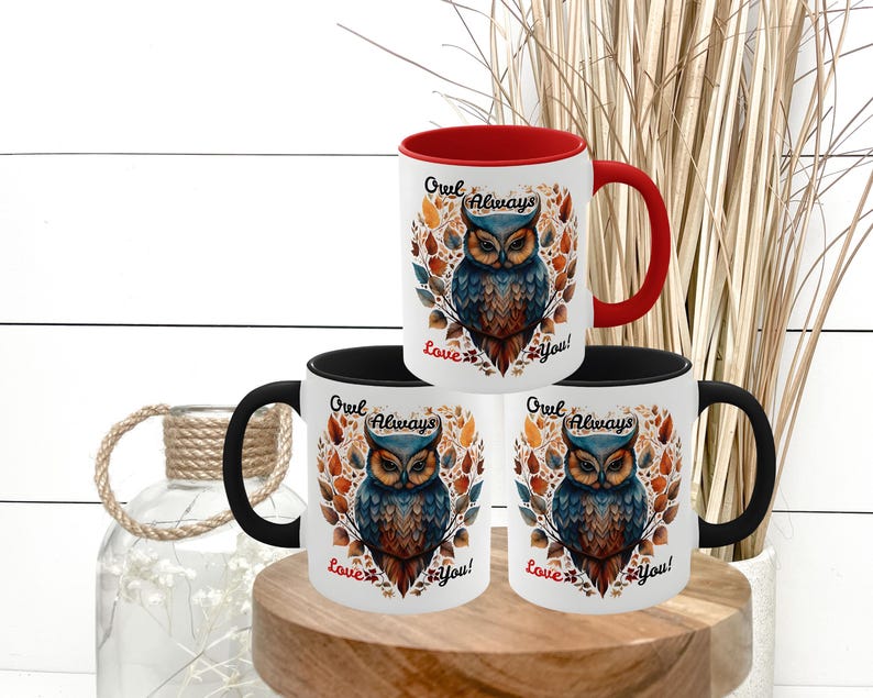 May include: White ceramic mugs with a colorful owl design. The owl is depicted with blue, brown, and orange feathers, surrounded by autumn leaves. The mugs have black and red handles and the text "Owl Always Love You!"