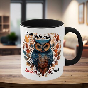May include: White ceramic mug with a black interior and handle. The mug features a colorful illustration of an owl surrounded by leaves, with the words "Owl Always Love You!" in script.