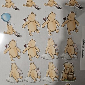 May include: A collection of Winnie the Pooh-themed stickers. The stickers feature Pooh Bear in various poses, including holding a blue balloon, with a butterfly, sitting on a cloud, and with a honey pot. The stickers are in a cartoon style.