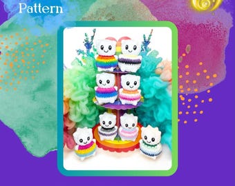 Puede incluir: Una colección de ocho pequeñas figuras de peluche tejidas a ganchillo en color blanco con caras bordadas, cada una con una base de rayas de diferentes colores que representan varias banderas del orgullo, dispuestas en un soporte con el texto PDF Pattern Pride Pal.