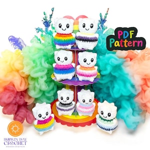 Op de afbeelding: Een verzameling gehaakte schaapjes met kleurrijke regenboogrokken. De poppen worden getoond op een regenboogkleurige etagère. De afbeelding bevat de tekst "PDF Pattern" en het logo van Hookin Day Crochet.