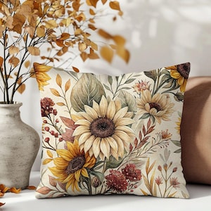May include: Square decorative pillow with a watercolor floral design featuring sunflowers in shades of yellow, brown, and green. The pillow has a cream-colored background and is surrounded by other decorative elements.