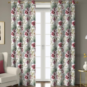 May include: Floral print curtains with a white background, featuring large burgundy and white flowers, and green leaves. The curtains hang in front of a white door, with a gold curtain rod. A white armchair with a pink pillow is to the left.