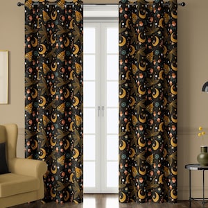 May include: Black curtain panels with a repeating pattern of gold moons, stars, and stylized moths. The design includes accents of orange, blue, and white. The curtains are hanging in front of a white door.