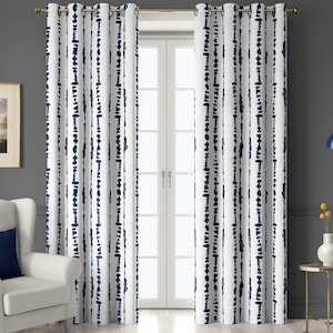 May include: White curtains with a navy blue vertical dotted stripe pattern. The curtains are hanging on a gold rod in front of a white door. A white armchair with a navy blue pillow is to the left.