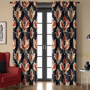 May include: A pair of black curtains with a repeating pattern of stylized floral shapes in shades of orange and cream. The curtains are hanging in front of a glass door, and the room has a red armchair and a small side table.