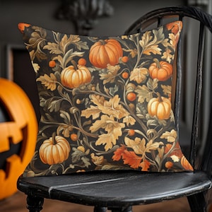 May include: A black throw pillow with a fall-themed design featuring orange pumpkins, brown leaves, and green vines. The pillow is sitting on a black wooden chair.