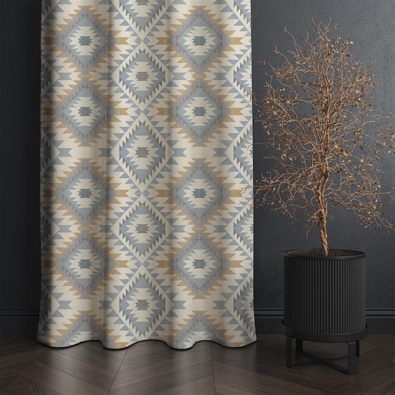 May include: A patterned curtain with a geometric design in shades of blue, beige, and gold. The curtain hangs next to a dark wall and a potted plant with a bare, twiggy appearance. The curtain's pattern is a repeating diamond shape.