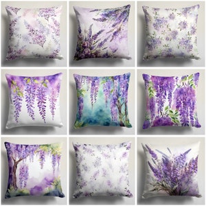May include: Nine decorative throw pillows with watercolor floral designs. The pillows feature various purple wisteria flower patterns on a white background. Some pillows have full wisteria branches, while others have scattered floral arrangements.