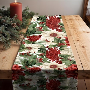 May include: White table runner with a floral pattern featuring red berries, white flowers, and green leaves. The runner is perfect for a holiday table setting.