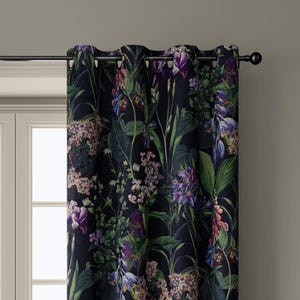 May include: Dark navy curtain with a vibrant floral pattern. The design features a variety of flowers in shades of purple, pink, and white, set against lush green foliage. The curtain is hung on a black rod and has metal grommets.