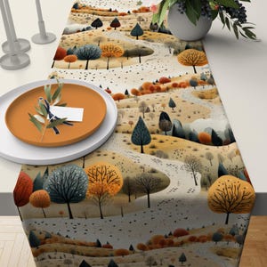 May include: A table runner with a whimsical woodland scene. The design features a winding path through a forest of trees with brown, orange, and green leaves. The background is a light gray with a subtle texture.