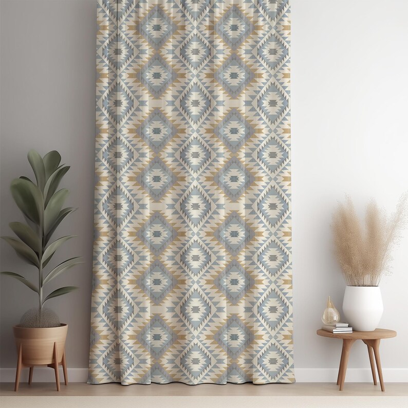 May include: A patterned curtain with a geometric design in shades of beige, gray, and gold. The curtain is hanging in front of a white wall. The pattern is a repeating diamond shape.