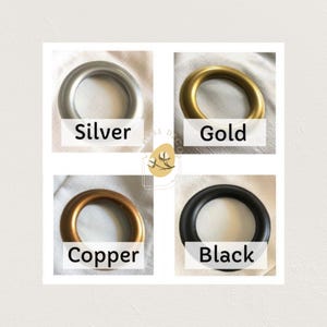 May include: Four metal curtain rings in silver, gold, copper, and black. Each ring is circular with a smooth finish. The colors are labeled with white text on a white background. The rings are displayed on a white surface.