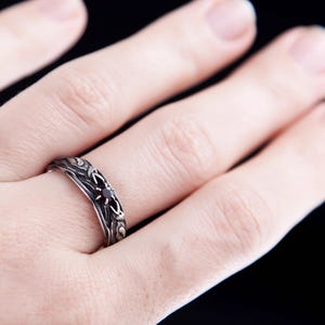 Sterling silver Viking ring featuring Odin's ravens Huginn and Muninn, holding a 3mm natural garnet. Handmade Norse mythology jewelry