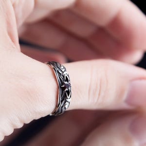 Sterling silver Viking ring featuring Odin's ravens Huginn and Muninn, holding a 3mm natural garnet. Handmade Norse mythology jewelry