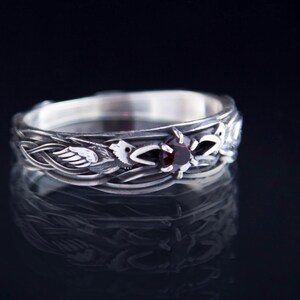 Sterling silver Viking ring featuring Odin's ravens Huginn and Muninn, holding a 3mm natural garnet. Handmade Norse mythology jewelry
