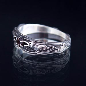Sterling silver Viking ring featuring Odin's ravens Huginn and Muninn, holding a 3mm natural garnet. Handmade Norse mythology jewelry