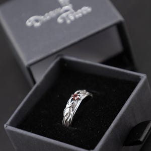 Sterling silver Norse raven ring resting in an open black velvet-lined Dream Tower jewelry box, viewed from above on a dark surface