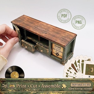 May include: A miniature wooden media console with a dark brown top and distressed green base, featuring two small drawers and a cabinet door with the text "HOME IS WHERE THE RECORDS PLAY". Includes a black vinyl record and printable paper sheets.