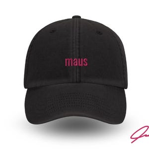 Könnte beinhalten: Schwarze Baseballkappe mit gebogenem Schirm. Das Wort "maus" ist in Pink auf der Vorderseite gestickt. Eine rosa Signatur befindet sich in der unteren rechten Ecke. Ein stilvolles Accessoire.
