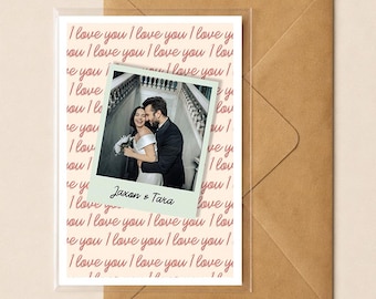 May include: A greeting card with a photo of a couple, with the words "I love you" in a repeating pattern. The photo is a Polaroid-style print with the names "Jaxon & Tara" at the bottom. The card is inside a clear sleeve, with a brown envelope.