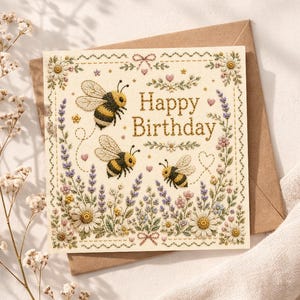 May include: A square greeting card with the text Happy Birthday in brown lettering. The design features three embroidered-style bees, lavender sprigs, and white daisies arranged in a border on a cream background, placed on a brown envelope.