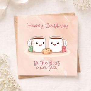 May include: A square greeting card with a light peach watercolor background featuring two white cartoon mugs with smiling faces, each holding a tea bag, and a small cookie between them. The text reads Happy Birthday to the best aun-tea.